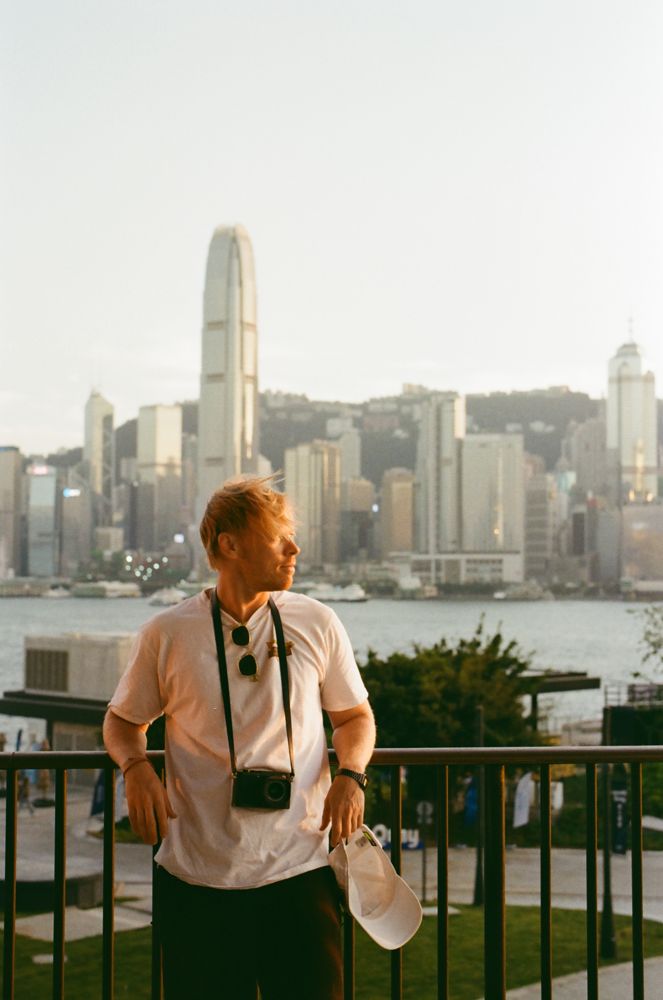 Self portrait at the harbour railing, holding a cap