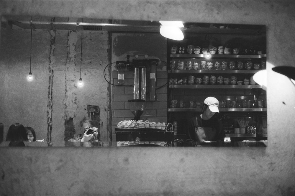 Barman behind the counter of a dim bar, black and white