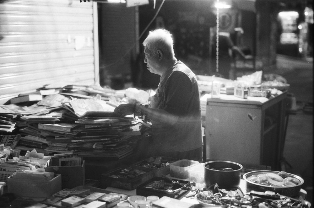 Man sorting papers in his night market stall